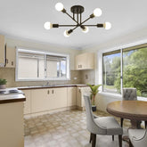 Modern kitchen with a chandelier, dining table, and chairs.